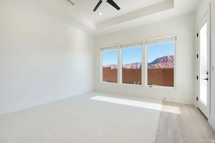 Bright interior space featuring three large windows, white walls, and light-colored carpet