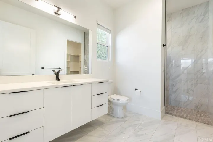 White vanity with integrated sink, matte black faucet, and expansive mirror
