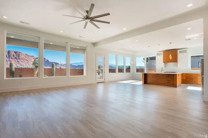 Expansive open-concept living area featuring light wood-finish flooring, recessed lighting, and a modern ceiling fan
