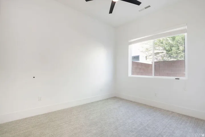 Spacious room featuring a large window, high ceilings, ceiling fan, carpet flooring, and white baseboards
