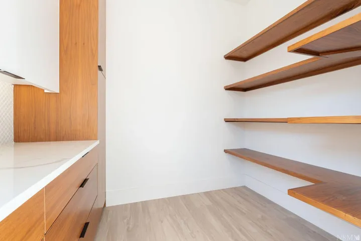 Integrated pantry shelving with warm wood-finish surfaces and durable wood-finish flooring