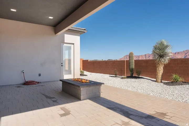 Outdoor patio featuring paver flooring, a built-in fire pit, covered ceiling with recessed lighting, xeriscaping with desert plantings, and a block wall perimeter