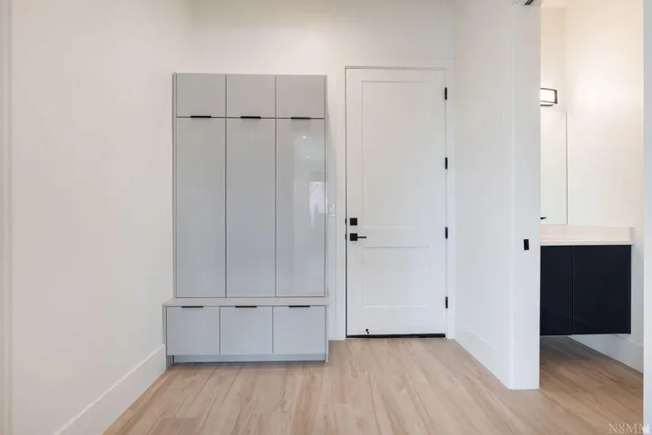 Entryway featuring light wood-finish flooring and a built-in storage unit with light gray cabinetry and integrated black pulls