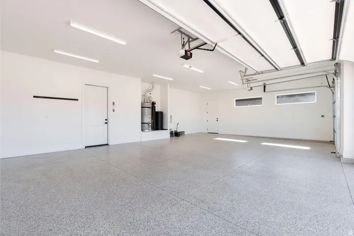Spacious garage featuring a durable epoxy floor coating, white painted walls, and ample overhead lighting