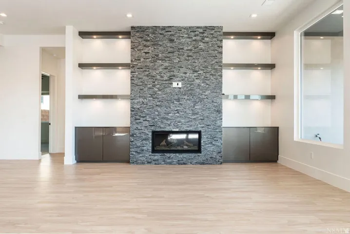Feature wall with a stone veneer fireplace and built-in shelving