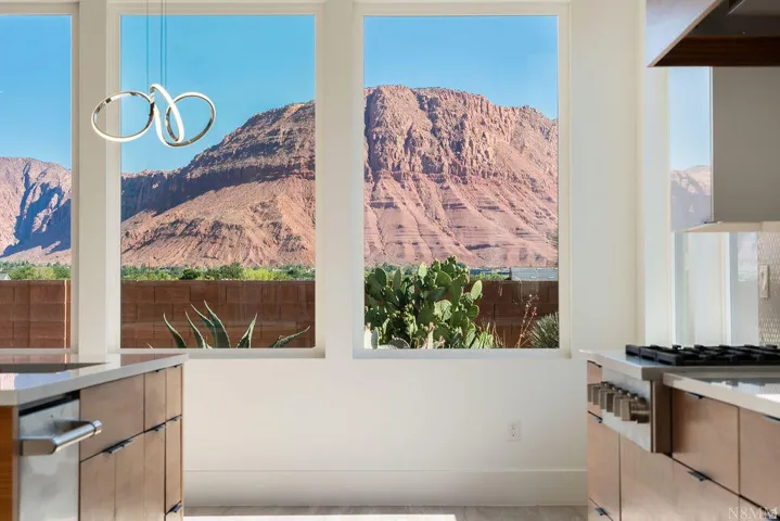 Contemporary kitchen featuring extensive natural light, wood-finish cabinetry, sleek countertops, and a modern range with a stainless steel hood