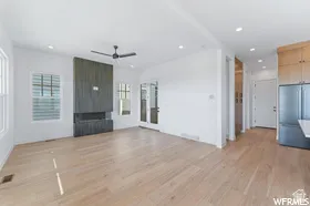 Bright living area featuring wide plank wood-finish flooring and a contemporary fireplace with a dark wood-paneled surround