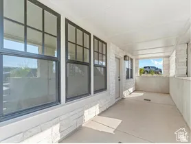 Covered porch featuring a white tongue-and-groove ceiling, white stone veneer siding, concrete flooring, and black-framed grid windows