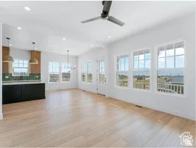 Open-concept living area with light wood-finish flooring, vaulted ceilings, and extensive windows providing abundant natural light