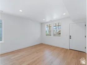Spacious room featuring light wood-finish flooring, recessed lighting, and white walls