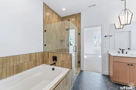 Bathroom featuring a built-in tub, a walk-in shower with clear glass enclosure and black hardware, hexagonal floor tiling, and a single vanity with a white countertop