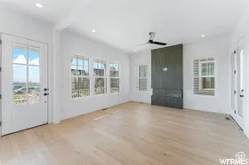 Spacious living area featuring light wood-finish flooring, a contemporary dark wood fireplace surround with an integrated electric fireplace, multiple large windows, and recessed lighting