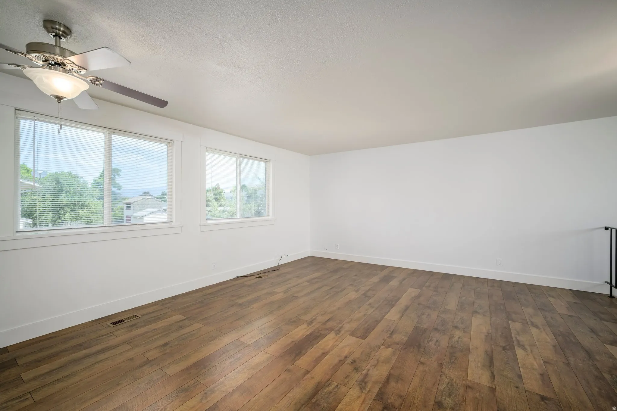 Spacious room featuring wood-finish flooring, white walls, and bright white trim