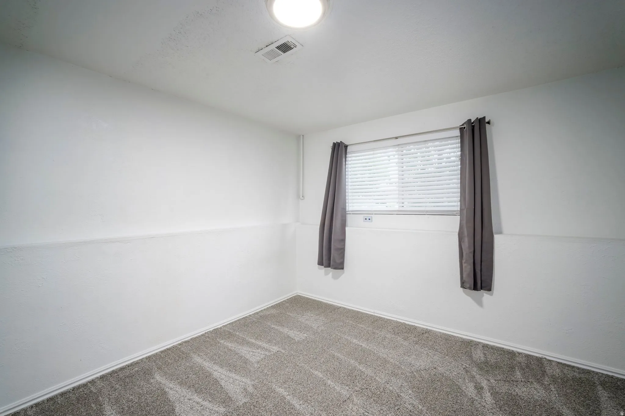 Neutral white walls with a textured finish, complemented by a light gray patterned carpet