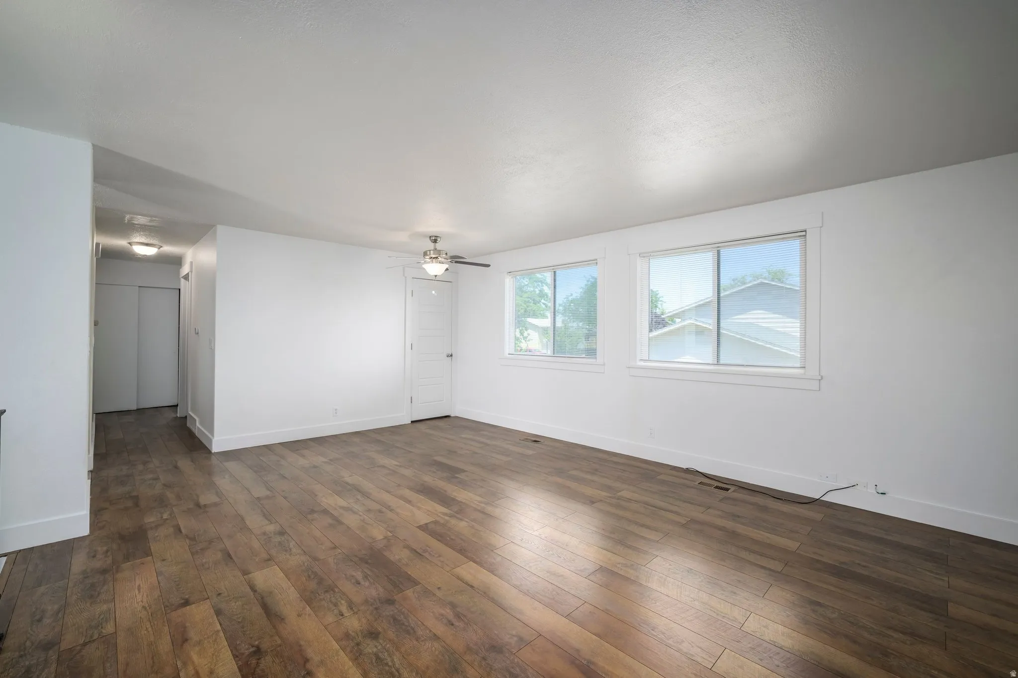 Spacious room featuring wood-finish flooring, white walls, and two windows