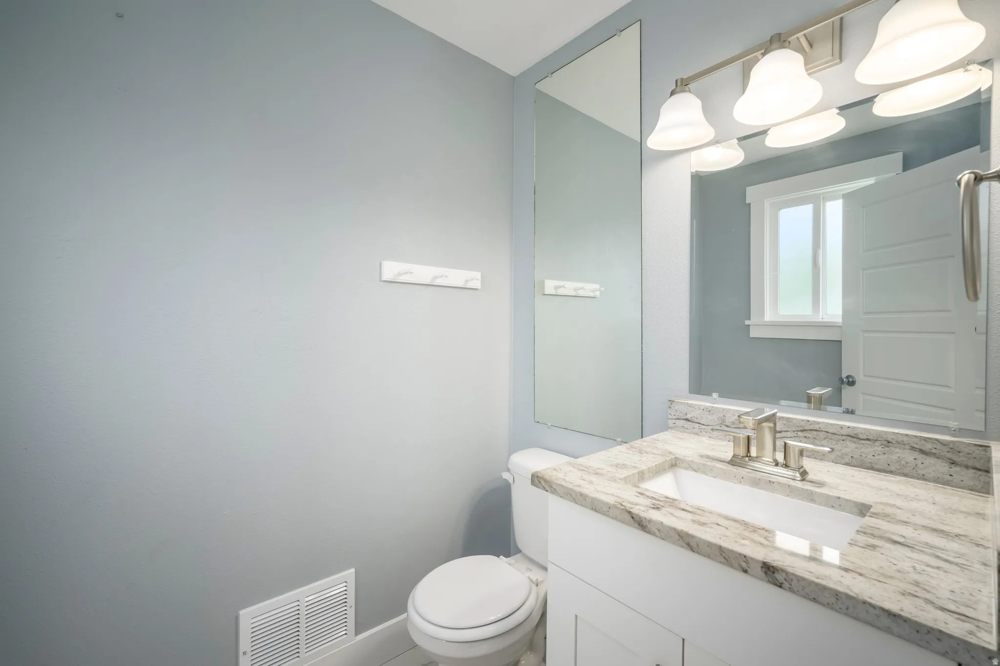 Bathroom featuring a single vanity with stone-finish countertop, undermount sink, and brushed nickel faucet