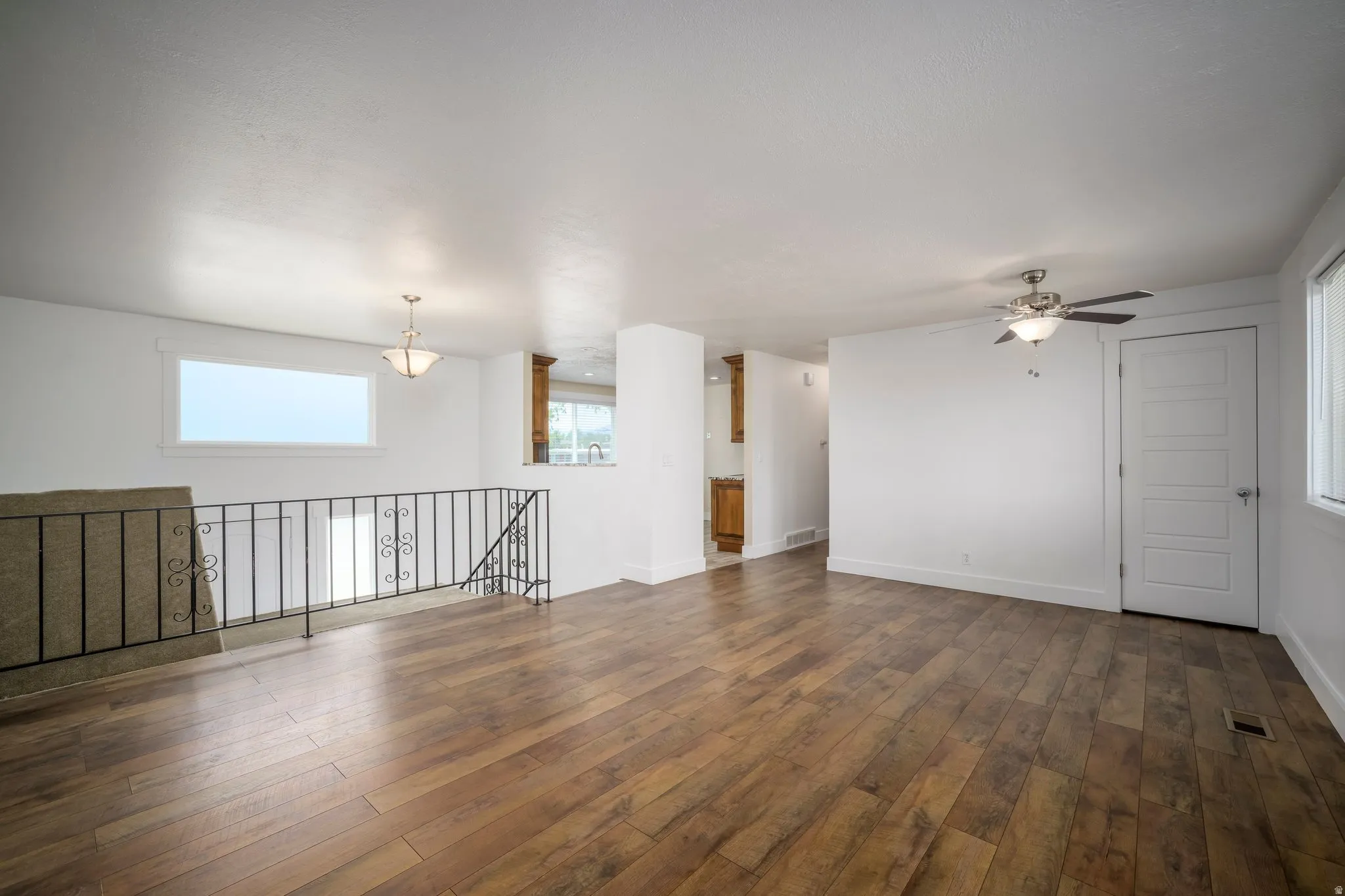 Spacious room featuring wood-finish flooring, white walls, and a recessed window