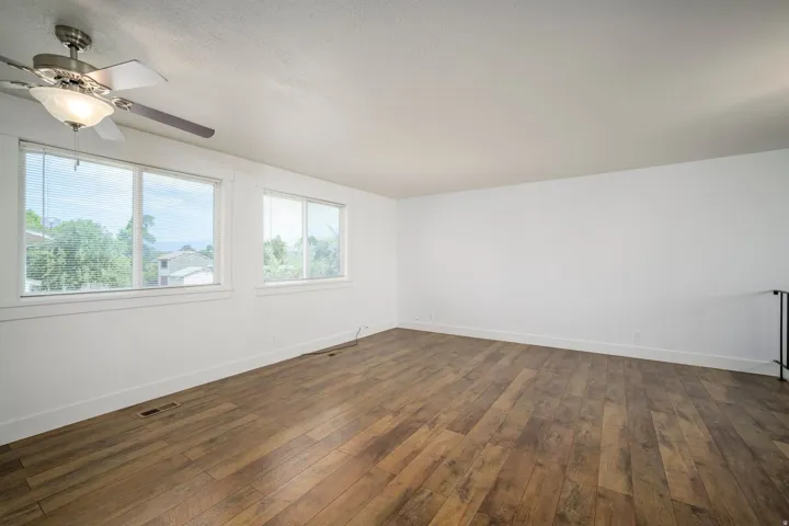 Spacious room featuring wood-finish flooring, white walls, and bright white trim