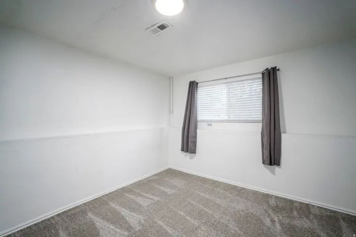 Neutral white walls with a textured finish, complemented by a light gray patterned carpet