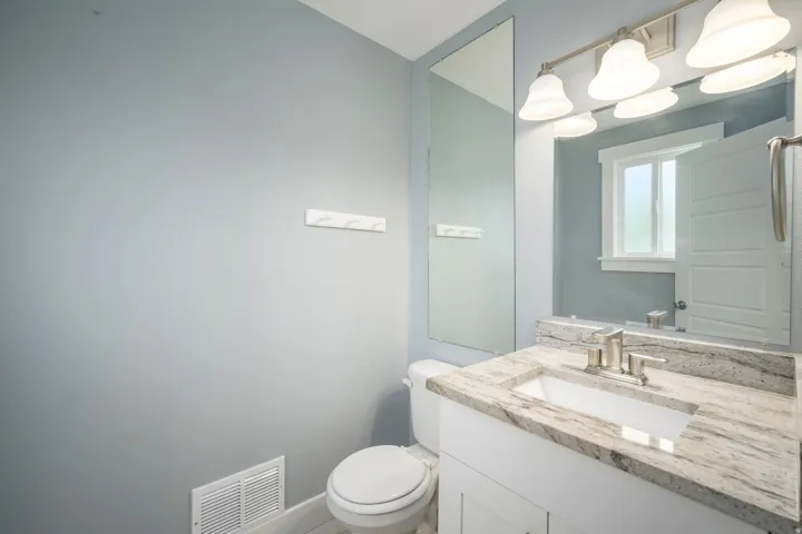 Bathroom featuring a single vanity with stone-finish countertop, undermount sink, and brushed nickel faucet