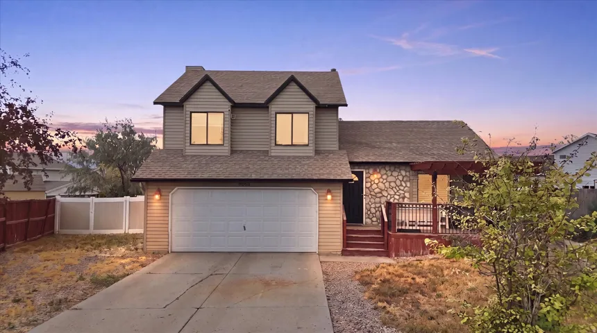 Two-story residence featuring light-toned siding, a stone facade accent, and a front-facing attached garage