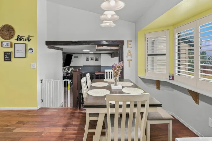 Dining area featuring wood-finish flooring and a bay window with plantation shutters