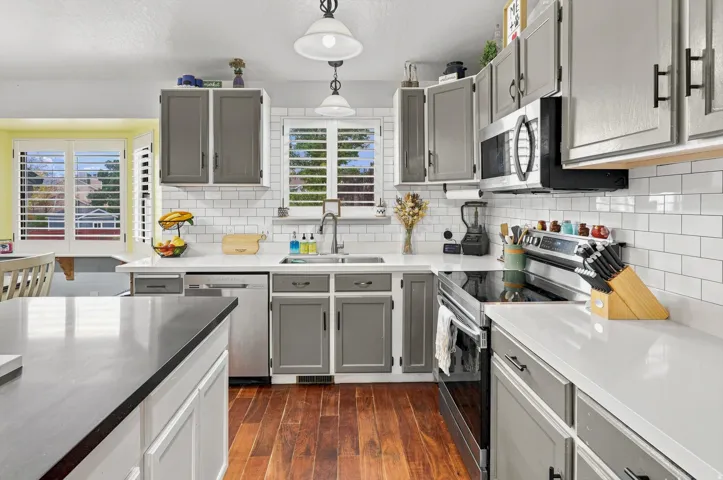 Kitchen featuring wood-finish flooring, white subway tile backsplash, white countertops, and gray cabinetry