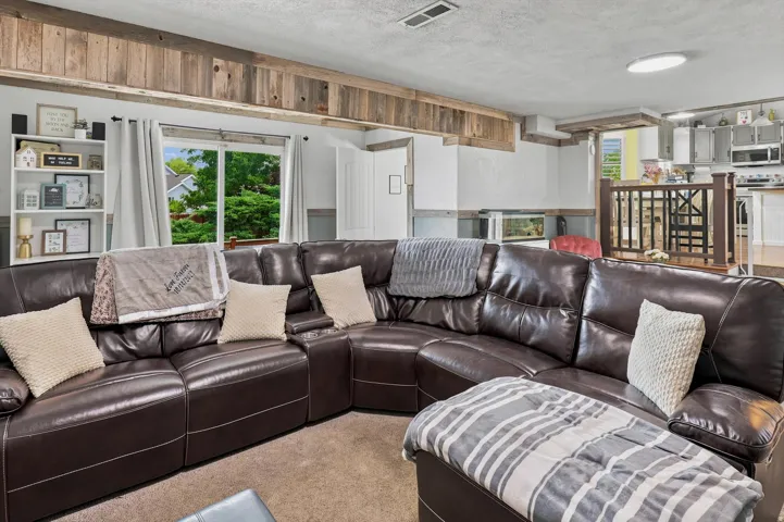 Open-concept living area featuring a large window, rustic wood-finish ceiling beams