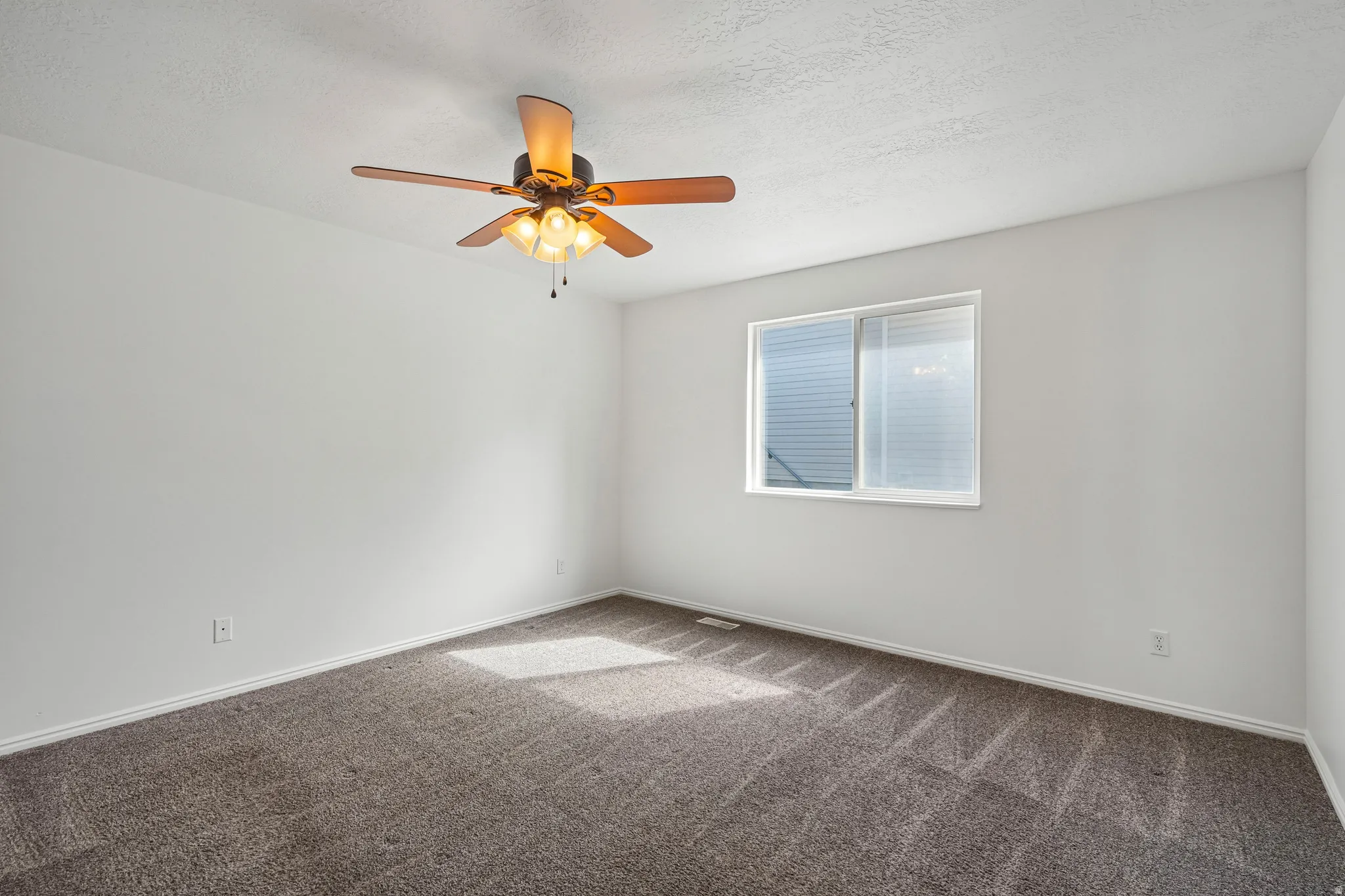 Interior room with textured white walls, a white ceiling, and dark gray carpet flooring