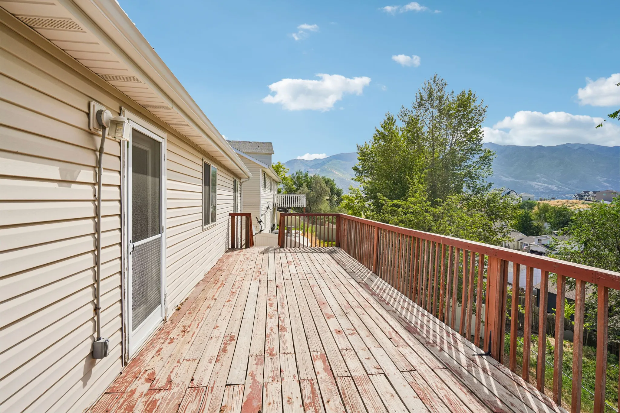 Expansive outdoor deck featuring wood flooring and a stained wood railing system