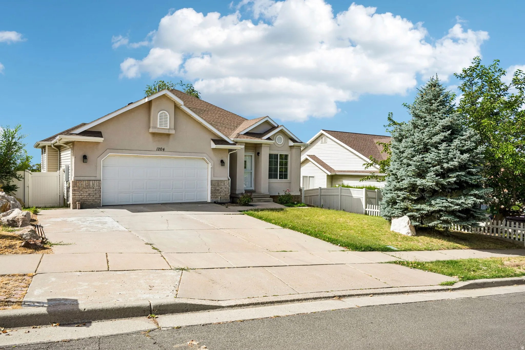 Ranch-style residence featuring a stucco and stone veneer facade, an attached two-car garage, and a concrete driveway