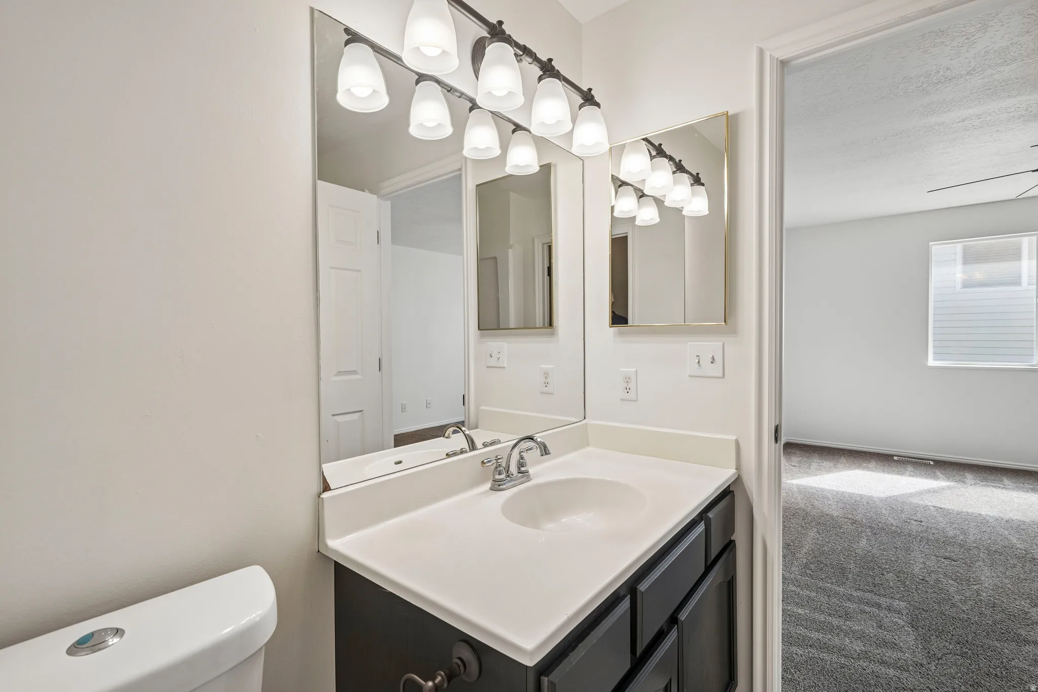 Bathroom vanity featuring a single basin sink, white countertop, and dark cabinetry