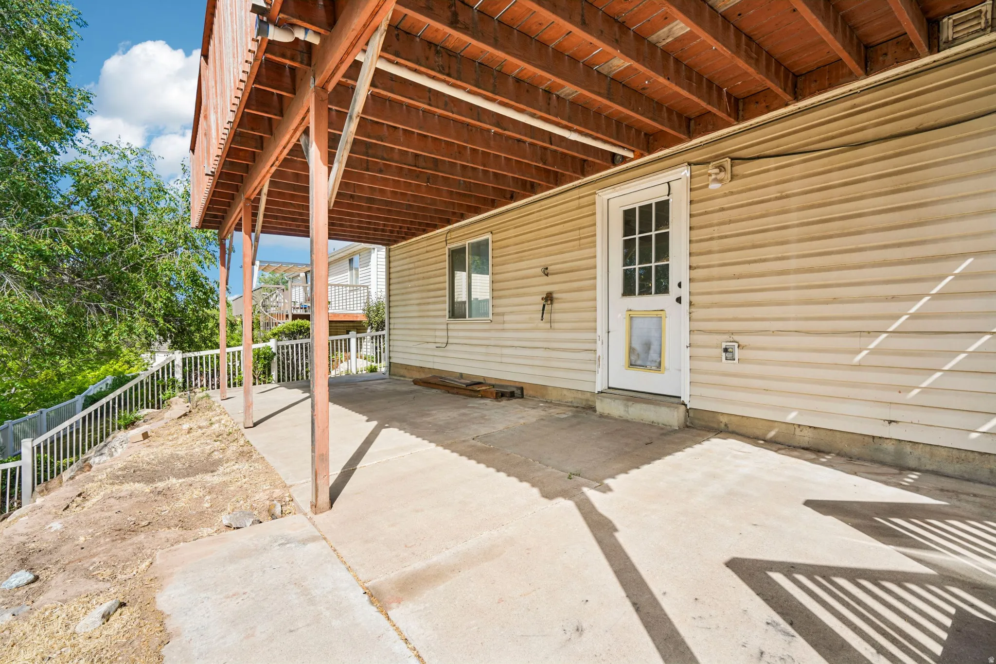 Covered concrete patio with wood structural supports and a white railing system