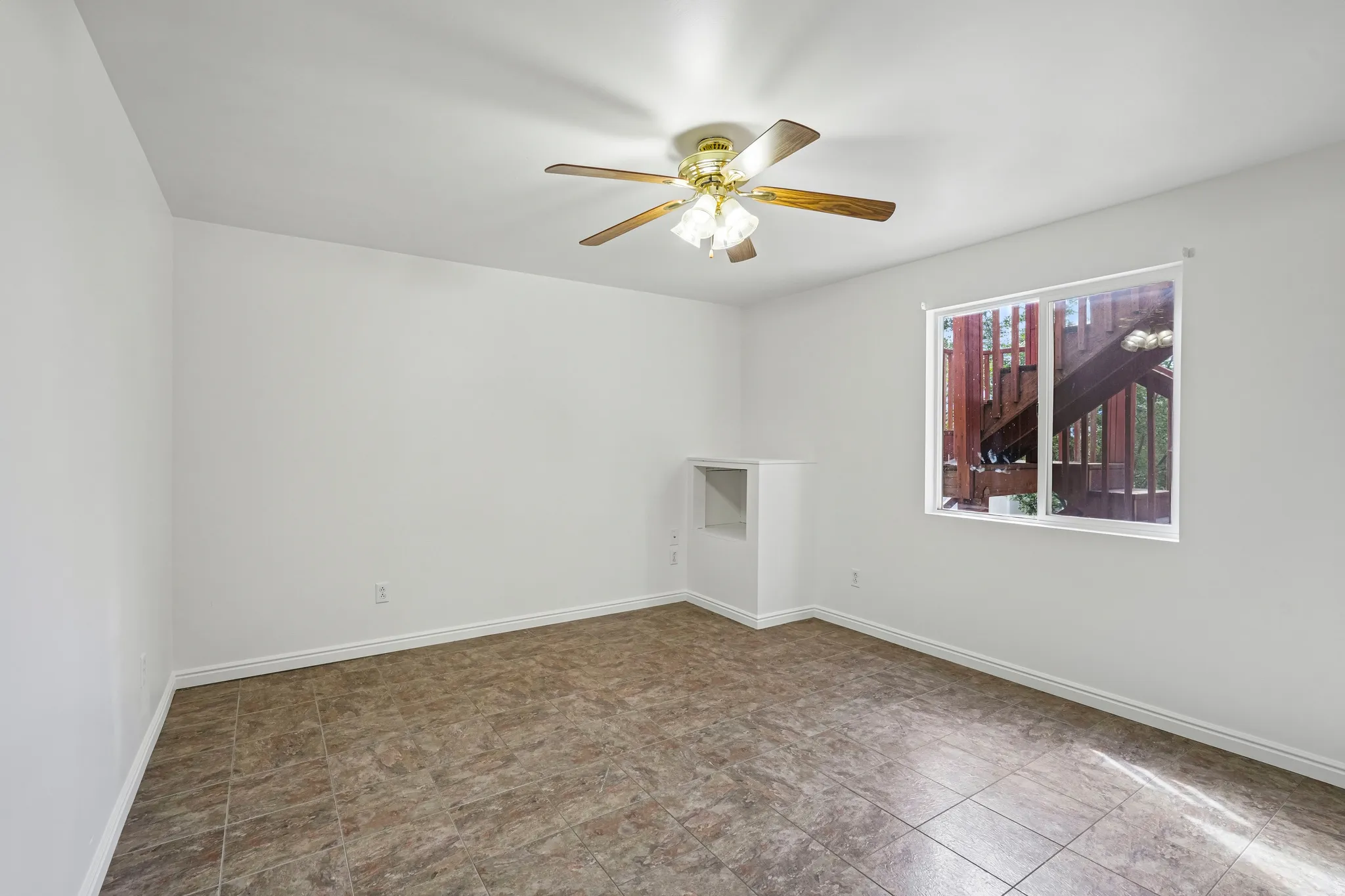 Neutral-toned tile flooring, white walls, and a ceiling fan with light fixture