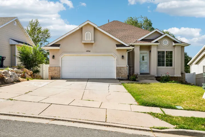 Stucco exterior residence featuring a two-car garage, brick veneer accents, and a covered front entry
