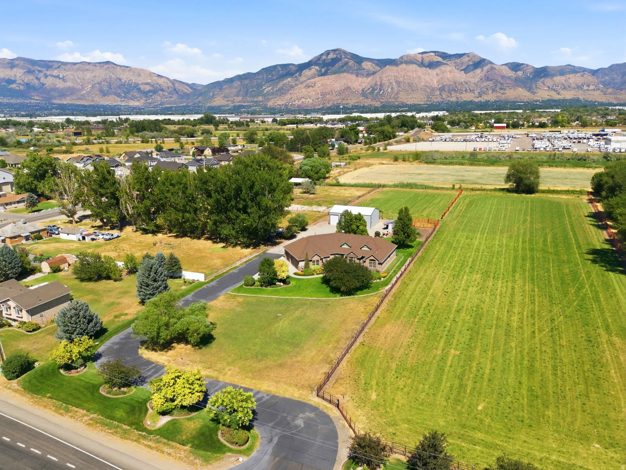Expansive property featuring a single-story residence with an attached garage, a detached workshop, and a large manicured field