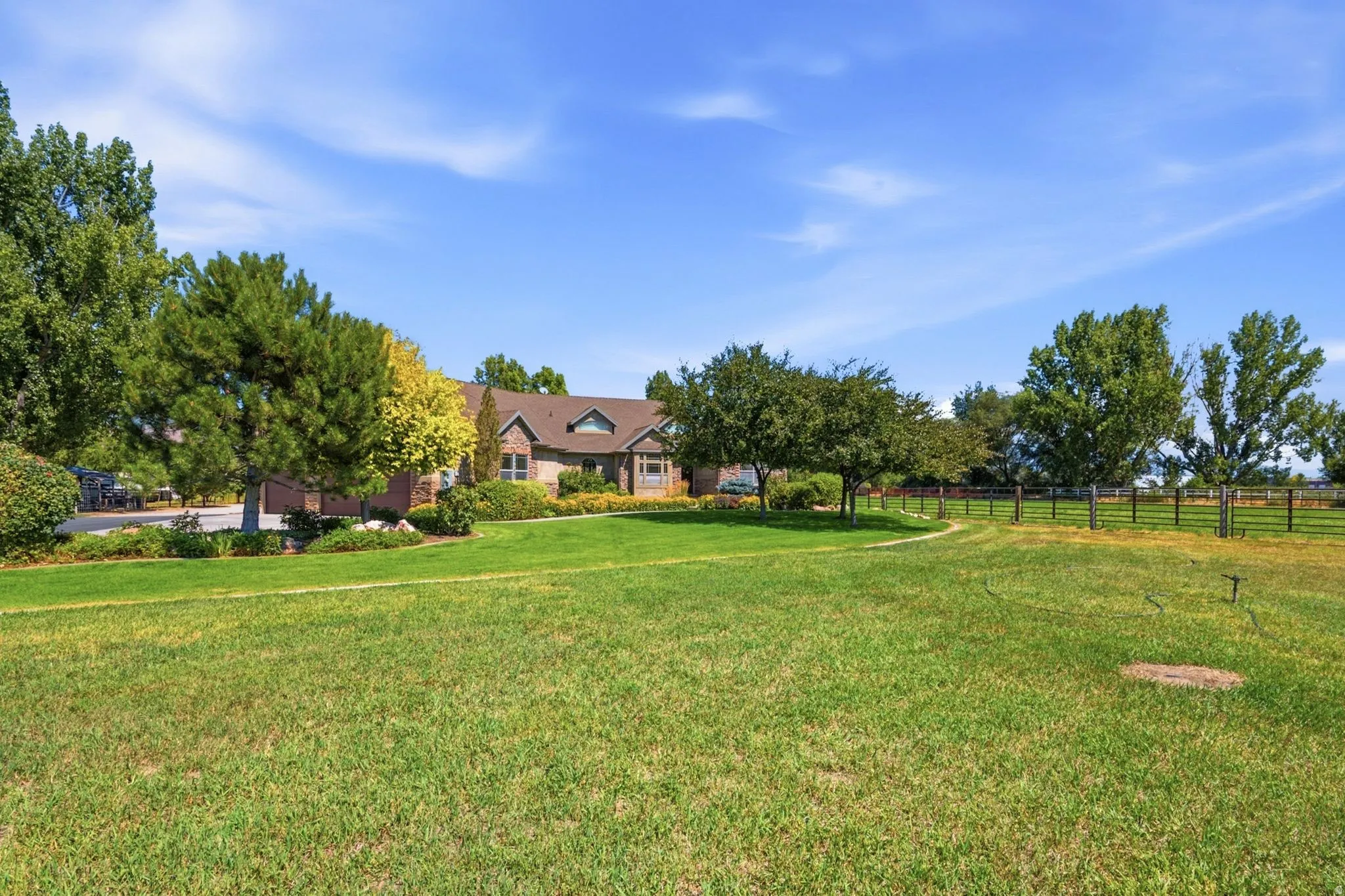 Expansive green lawn with mature trees and a distant fence line