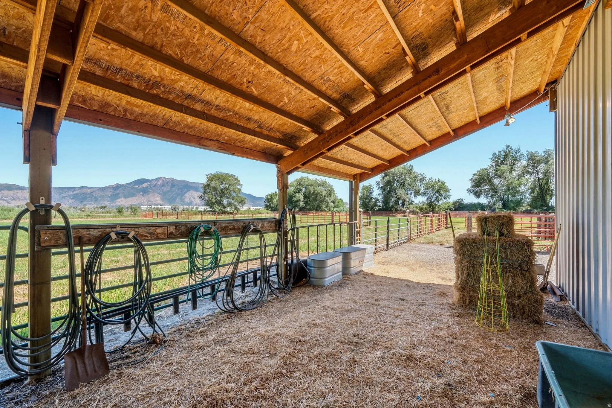 Covered outdoor area featuring a wood-beam ceiling, open-air design, and a corrugated metal wall