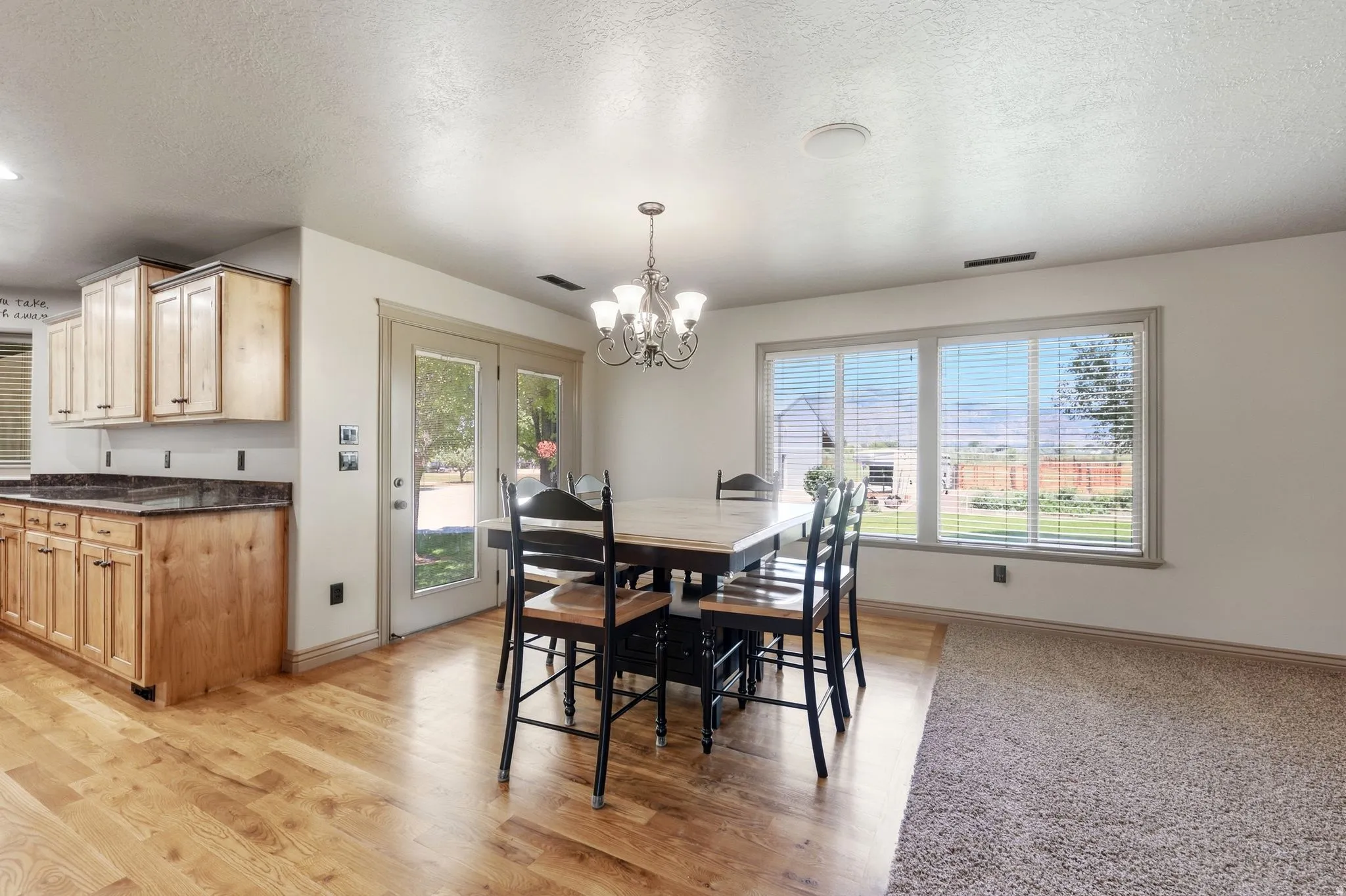 Dining area with wood-finish flooring transitioning to carpet