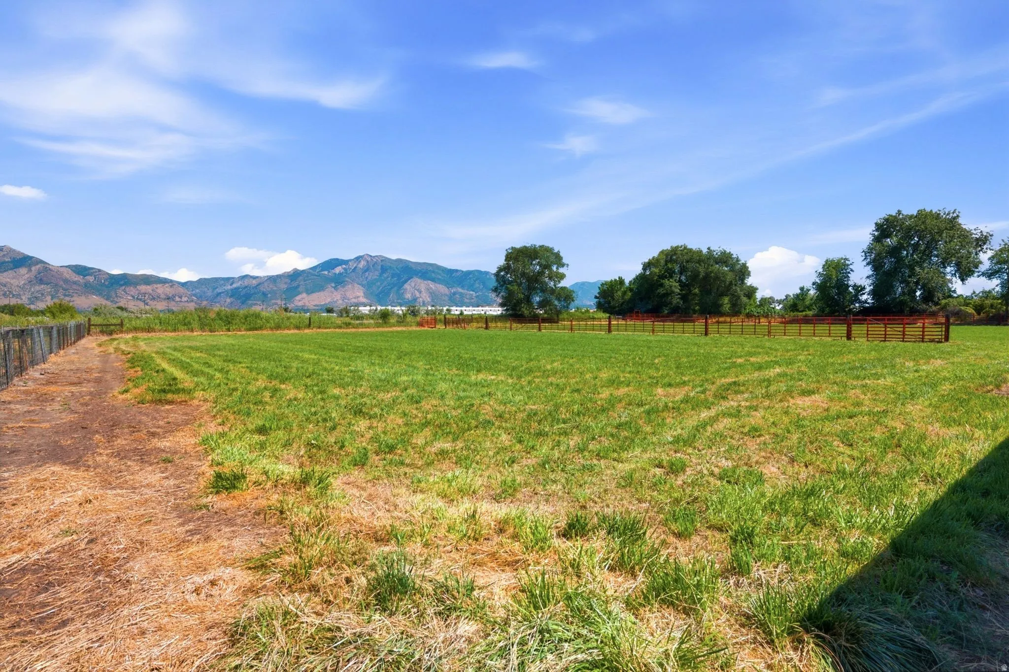 Expansive land parcel featuring green fields and partial fencing