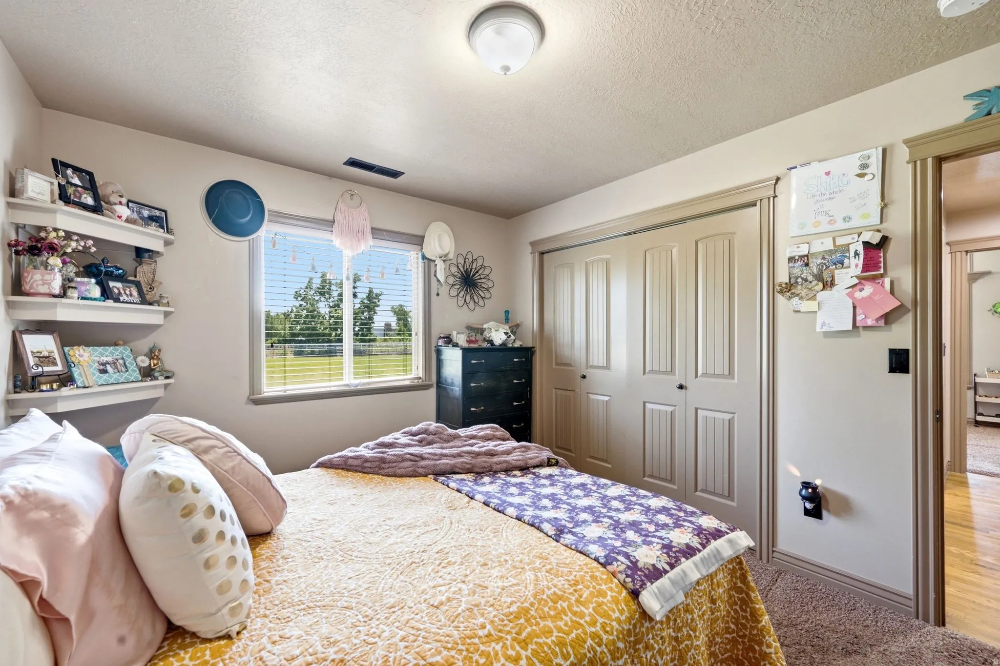 Bedroom featuring a horizontal window, three floating shelves, a ceiling-mounted light fixture, and bifold closet doors