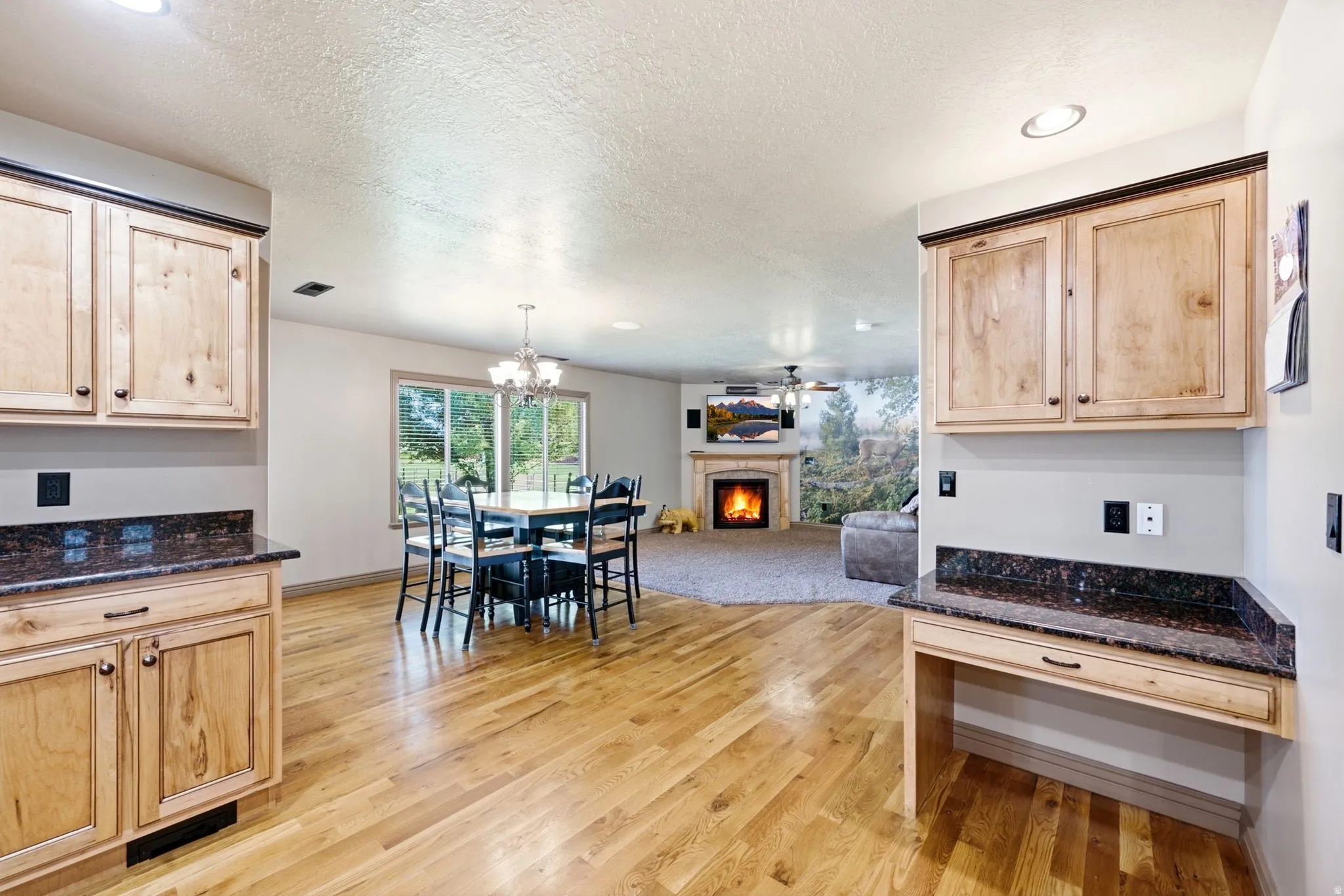 Open-concept living area with wood-finish flooring, custom wood cabinetry, and dark speckled countertops