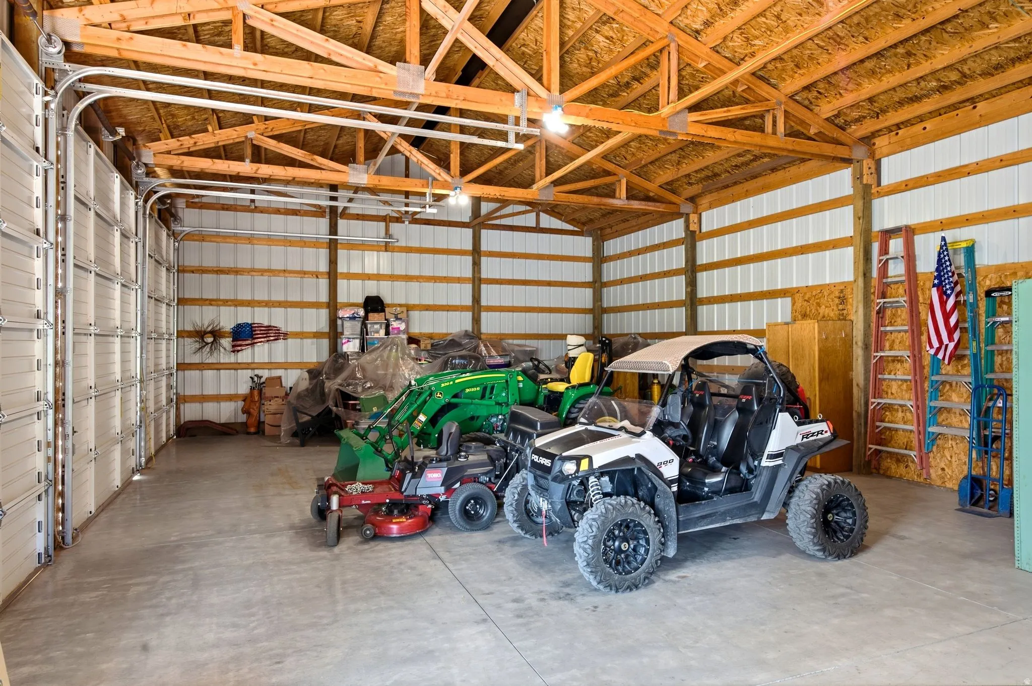 Spacious pole barn with concrete flooring, exposed wood truss ceiling, and metal panel walls