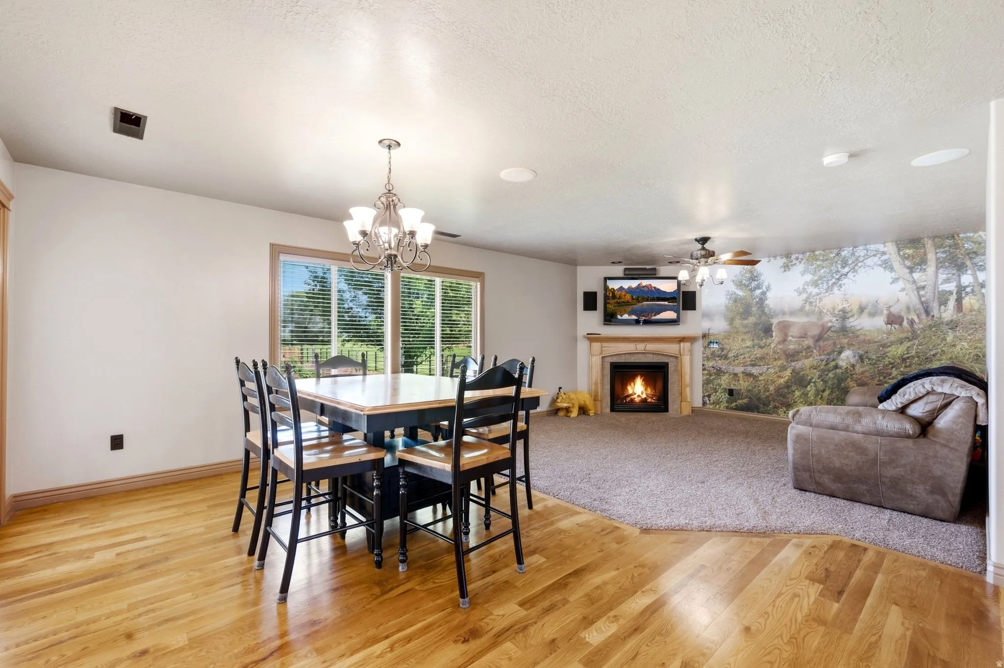 Combined living and dining areas featuring wood-finish flooring, a chandelier, and large windows with blinds