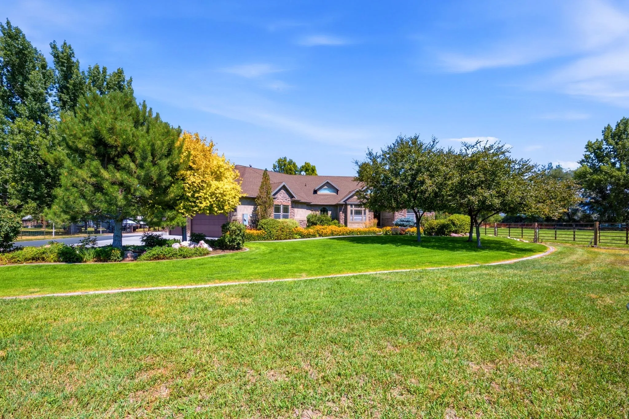 Expansive front lawn with mature trees and a fenced perimeter