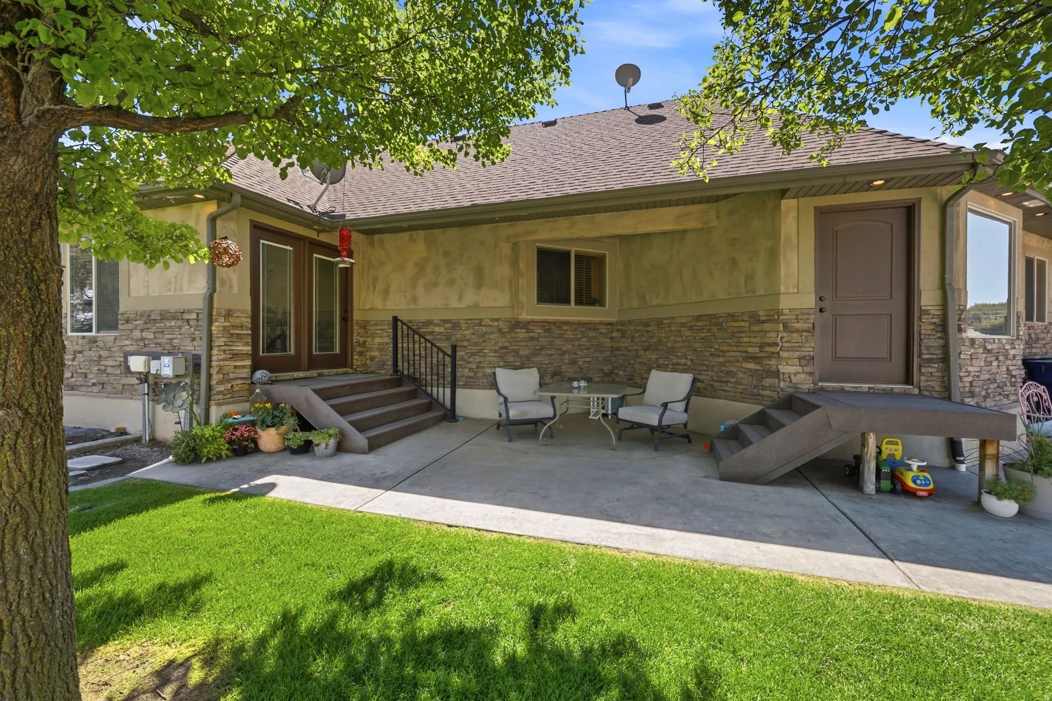 Expansive concrete patio area with two distinct entryways, surrounded by a manicured lawn