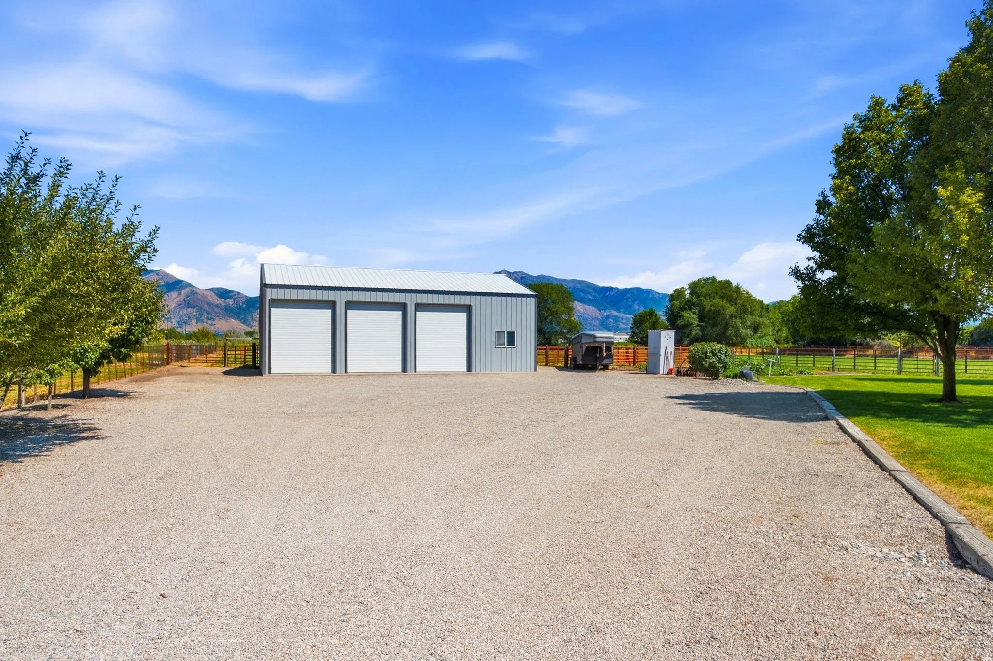 Metal outbuilding featuring three white garage doors and a light gray exterior