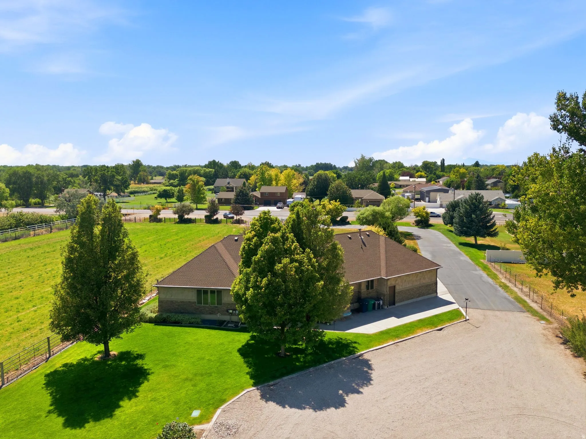 Expansive property featuring a single-story residence with a brown shingle roof and brick exterior
