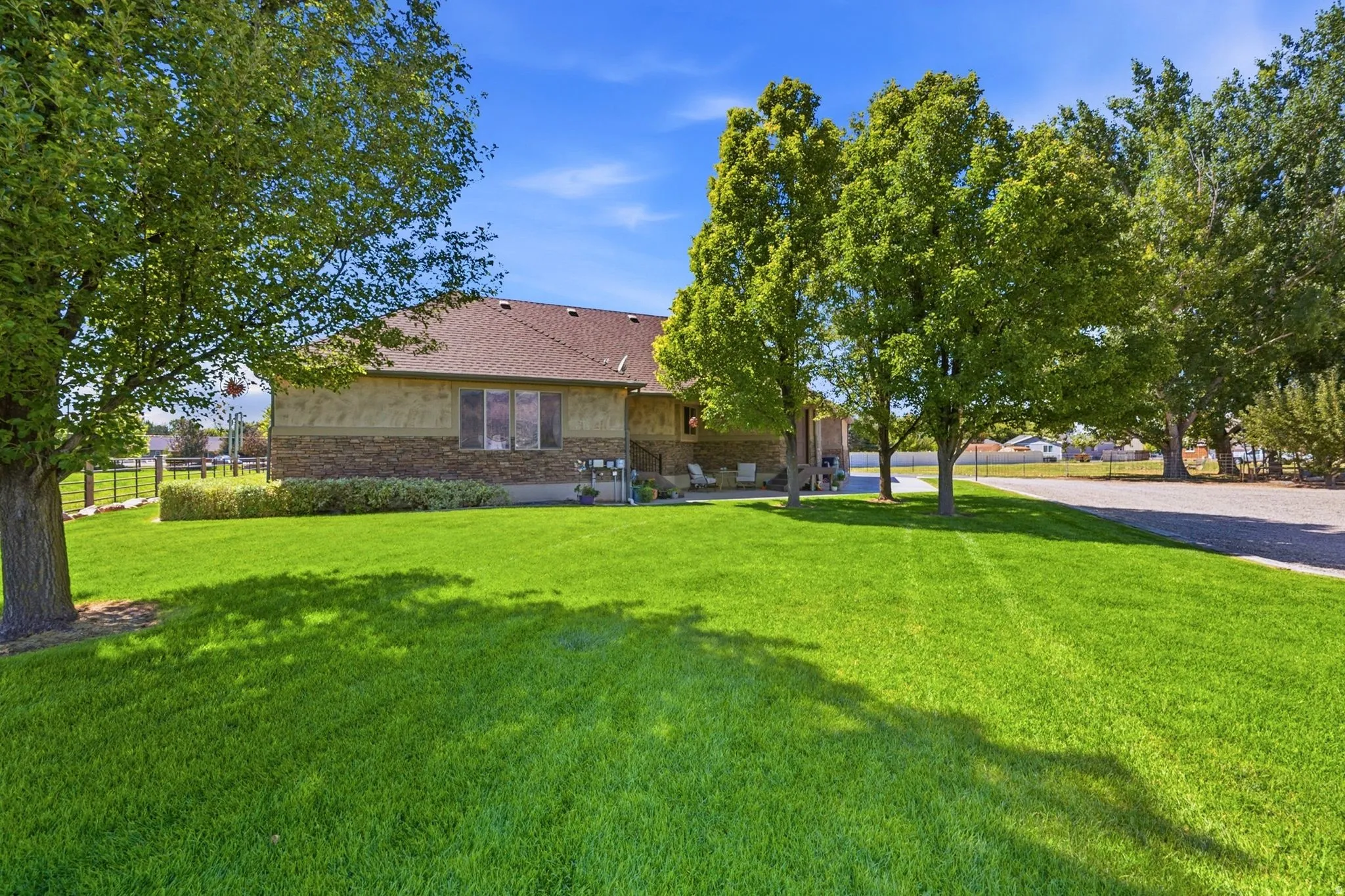 Expansive green lawn with mature trees and a stone-accented exterior