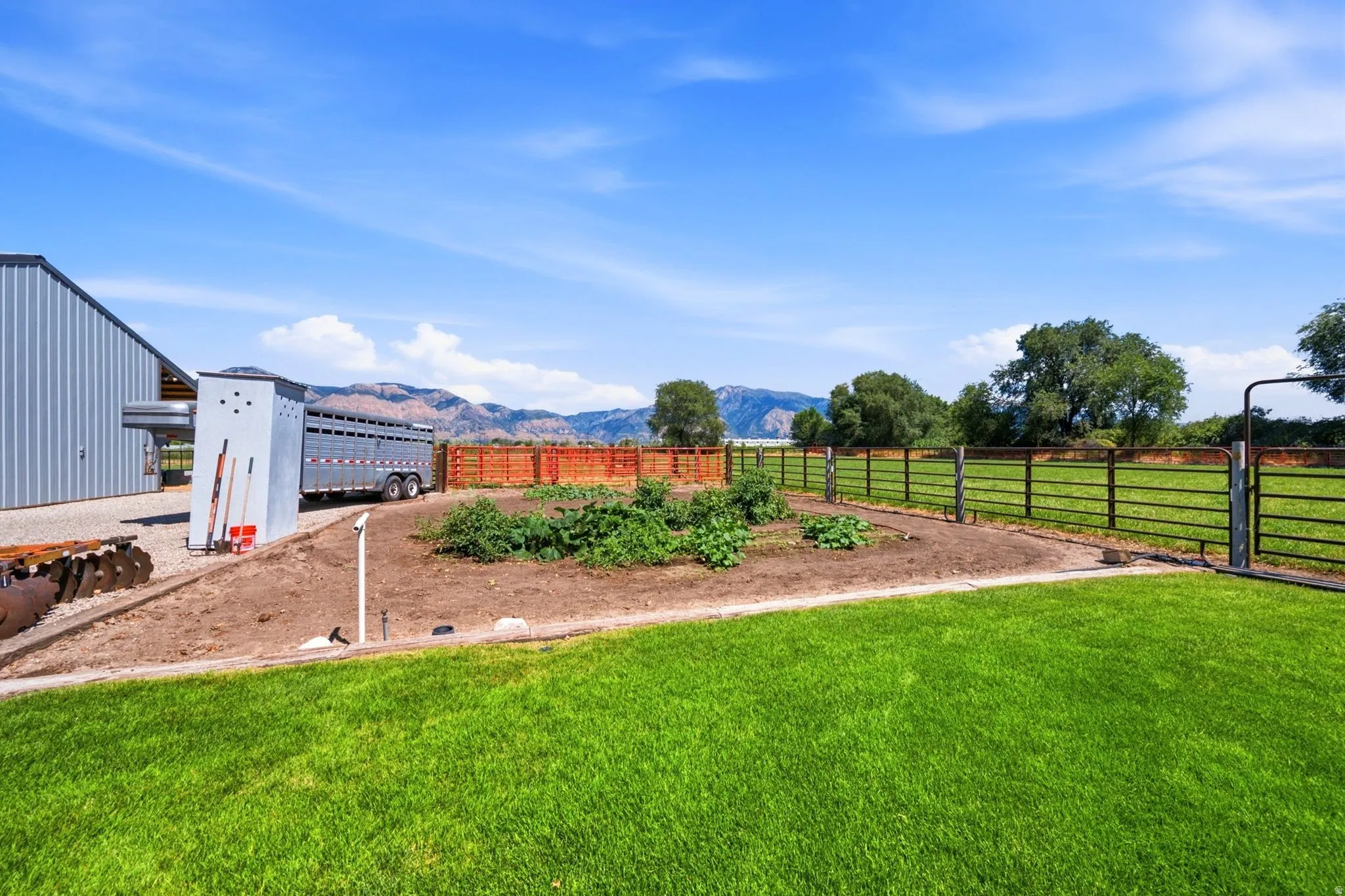 Expansive grassy area with a partial metal fence enclosure